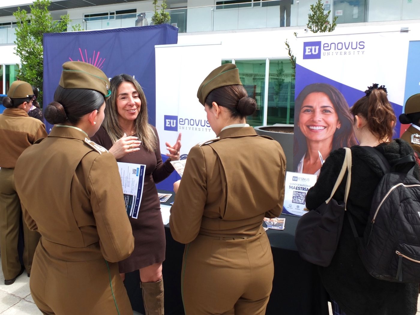 Funcionarias de Carabineros conversan con el equipo de Enovus University en el stand de la feria